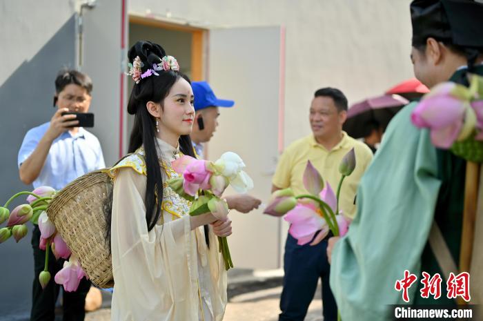 图为身着古装的表演者手持荷花巡游。 俞靖 摄 图为身着古装的表演者手持荷花巡游。 俞靖 摄