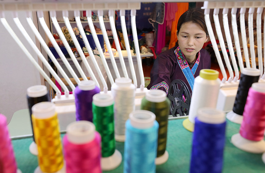 图为绣娘正在生产绣片。