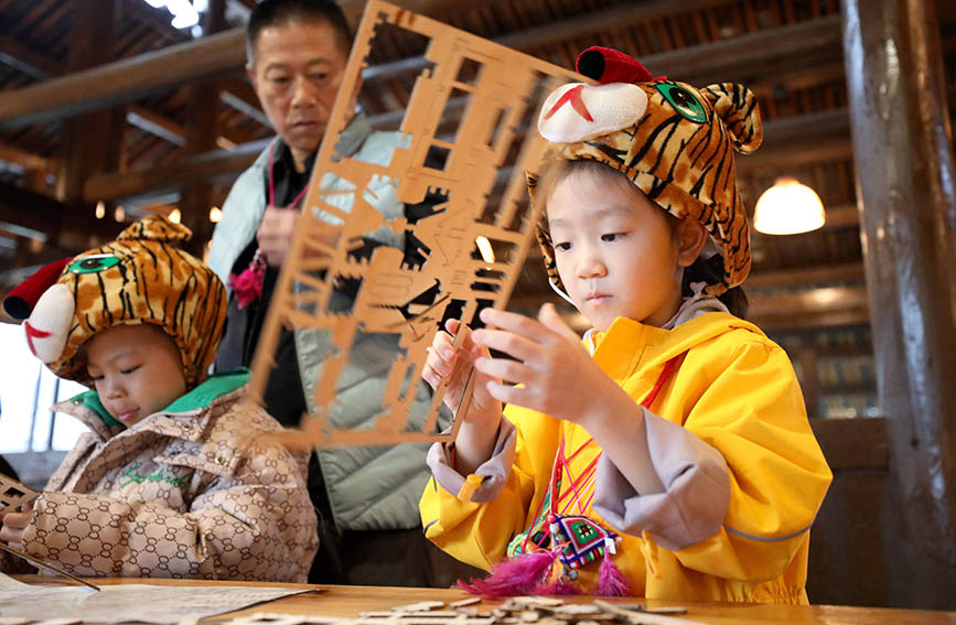 1月12日，一名“小东北虎”在侗族木构博物馆内拼装侗族鼓楼模型。